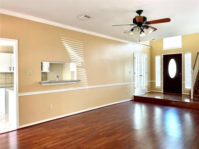 a view of a livingroom with wooden floor a ceiling fan and windows