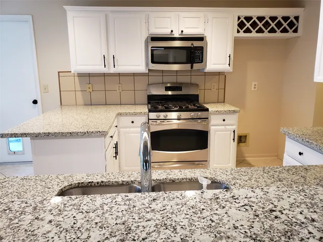 a kitchen with granite countertop white cabinets and a sink