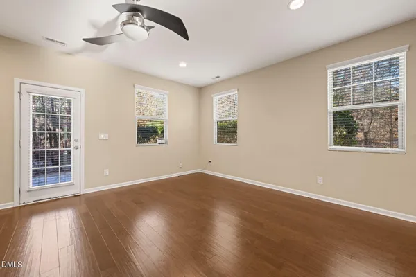 an empty room with wooden floor fireplace and windows