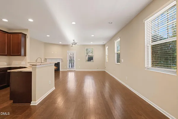 a view of an empty room with wooden floor fireplace and a window