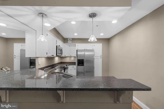 a kitchen with kitchen island granite countertop a sink a counter space appliances and cabinets