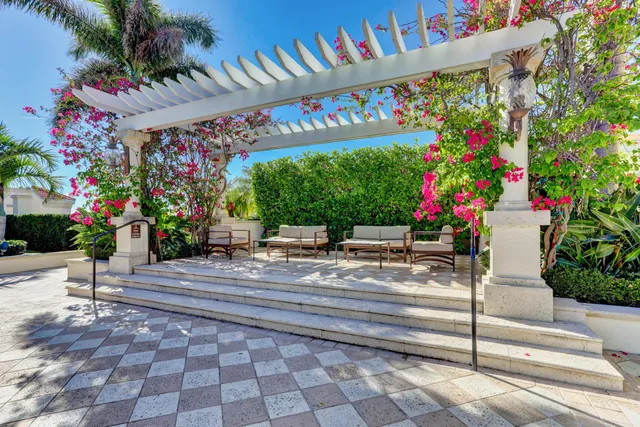a view of a patio with dining table and chairs with plants and palm trees