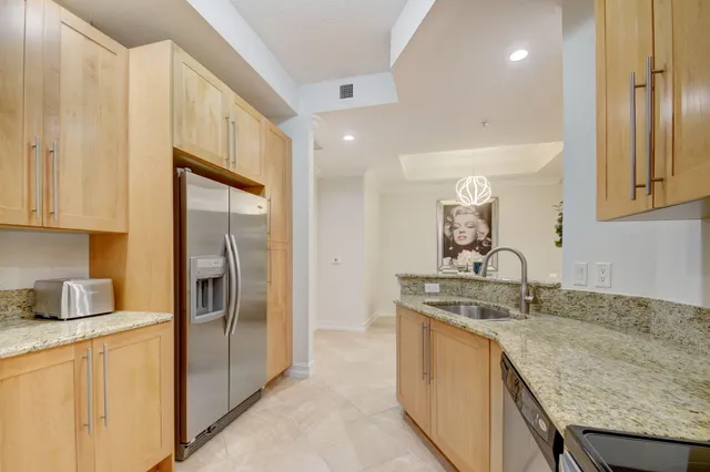 a kitchen with stainless steel appliances granite countertop a sink and a refrigerator