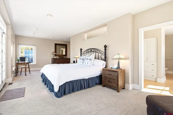 a spacious bedroom with a bed a table and windows