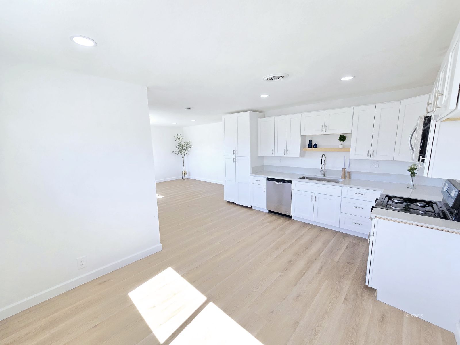 300 South Gordon Street Ridgecrest, CA 93555 - Photo 5 of 20 a kitchen with stainless steel appliances granite countertop a stove a sink and white cabinets with wooden floor