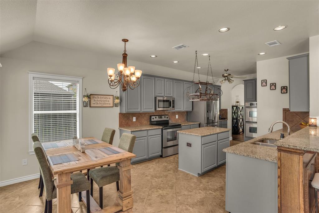 2309 Ranch House Drive Denton, TX 76210 - Photo 7 of 28 a open kitchen with kitchen island a stove a sink a refrigerator dining table and chairs