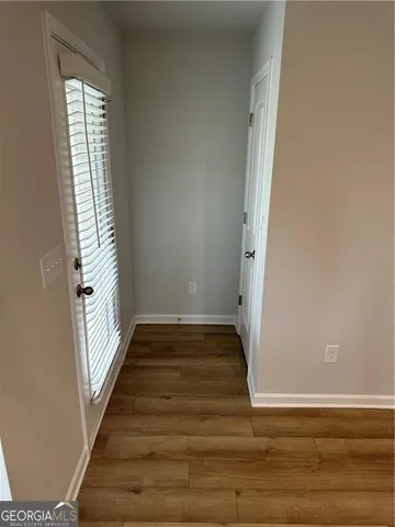 a view of an empty room with wooden floor and a window