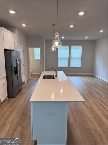 a large kitchen with stainless steel appliances a large counter top a stove and a wooden floors