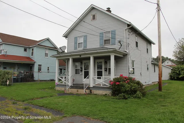 a view of a house with a yard plants and large tree