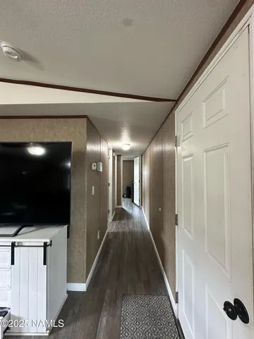 a view of a hallway with wooden floor and a flat screen tv
