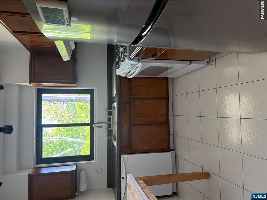 1375 River Road, Unit 1K Edgewater, NJ 07020 - Photo 10 of 15 a kitchen with stainless steel appliances granite countertop a stove a sink and a microwave