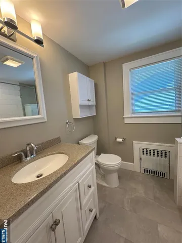 a bathroom with a granite countertop toilet sink mirror and vanity