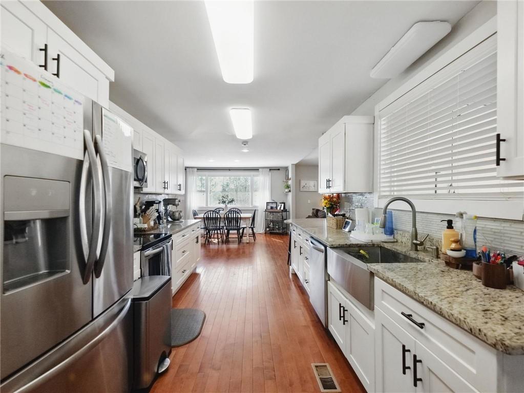 2093 Beverly Road Gainesville, GA 30501 - Photo 20 of 24 a kitchen with stainless steel appliances granite countertop a refrigerator a stove a sink dishwasher and white cabinets with wooden floor