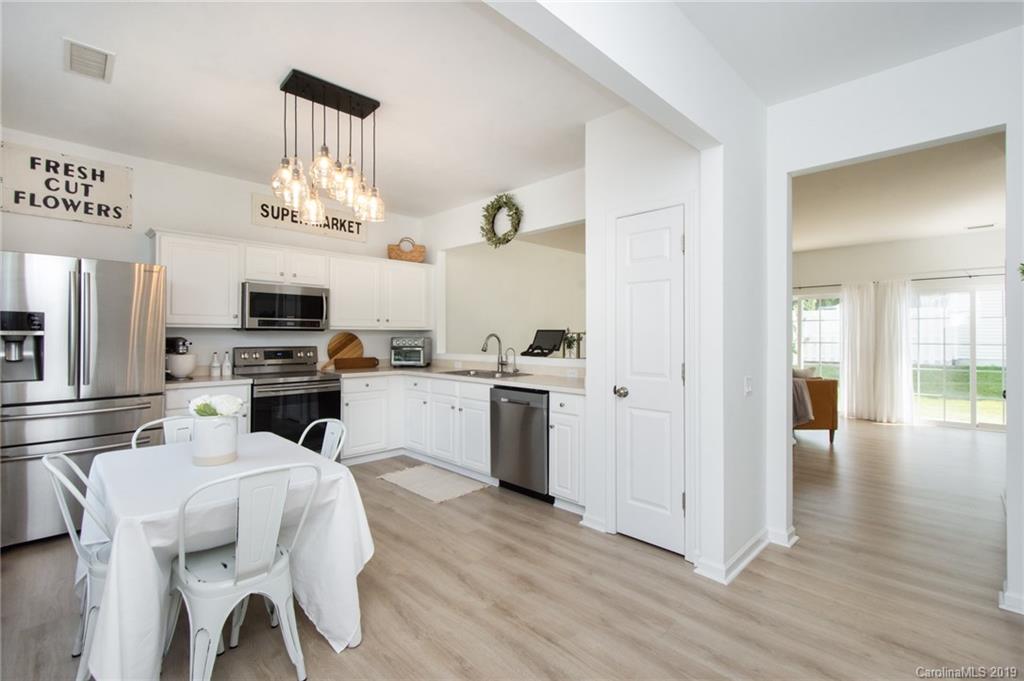 6864 Rothchild Drive Charlotte, NC 28270 - Photo 3 of 36 a kitchen with stainless steel appliances kitchen island granite countertop a refrigerator a stove and white cabinets with wooden floor