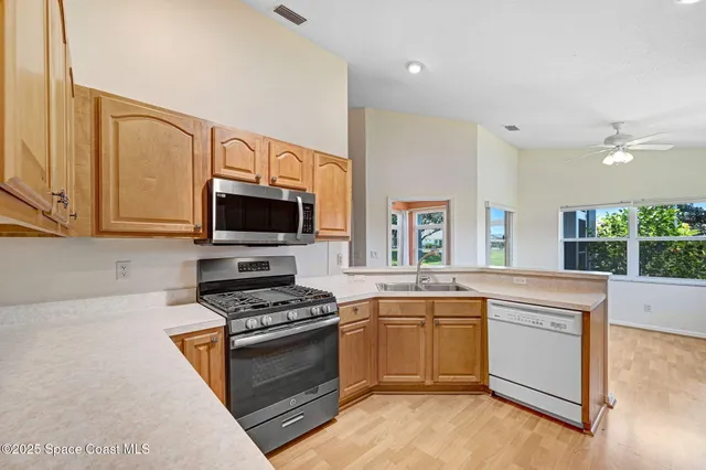 a view of an empty room with chandelier fan and wooden floor