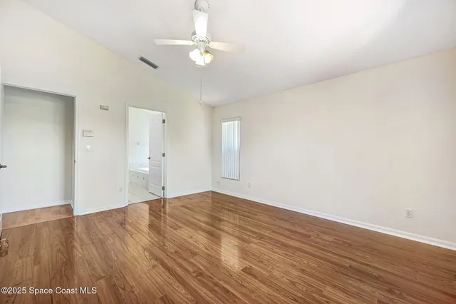 a view of an empty room with kitchen and window