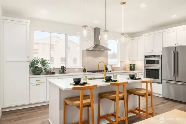 a kitchen with stainless steel appliances kitchen island granite countertop a table chairs and a refrigerator