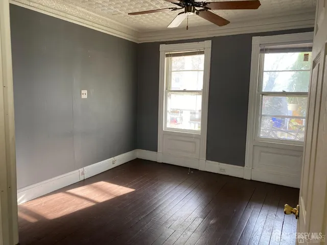 an empty room with wooden floor fan and windows