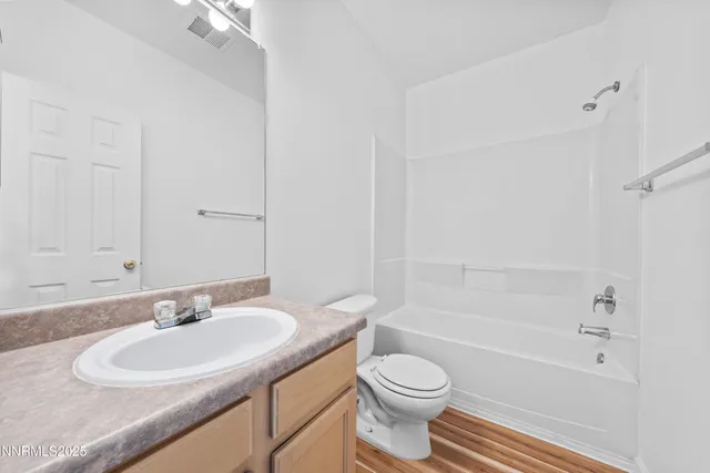 a bathroom with a granite countertop sink a toilet a mirror and a bathtub