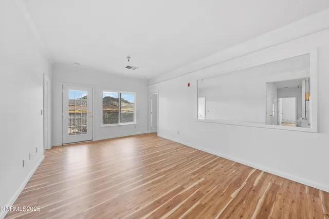 a view of an empty room with window and wooden floor