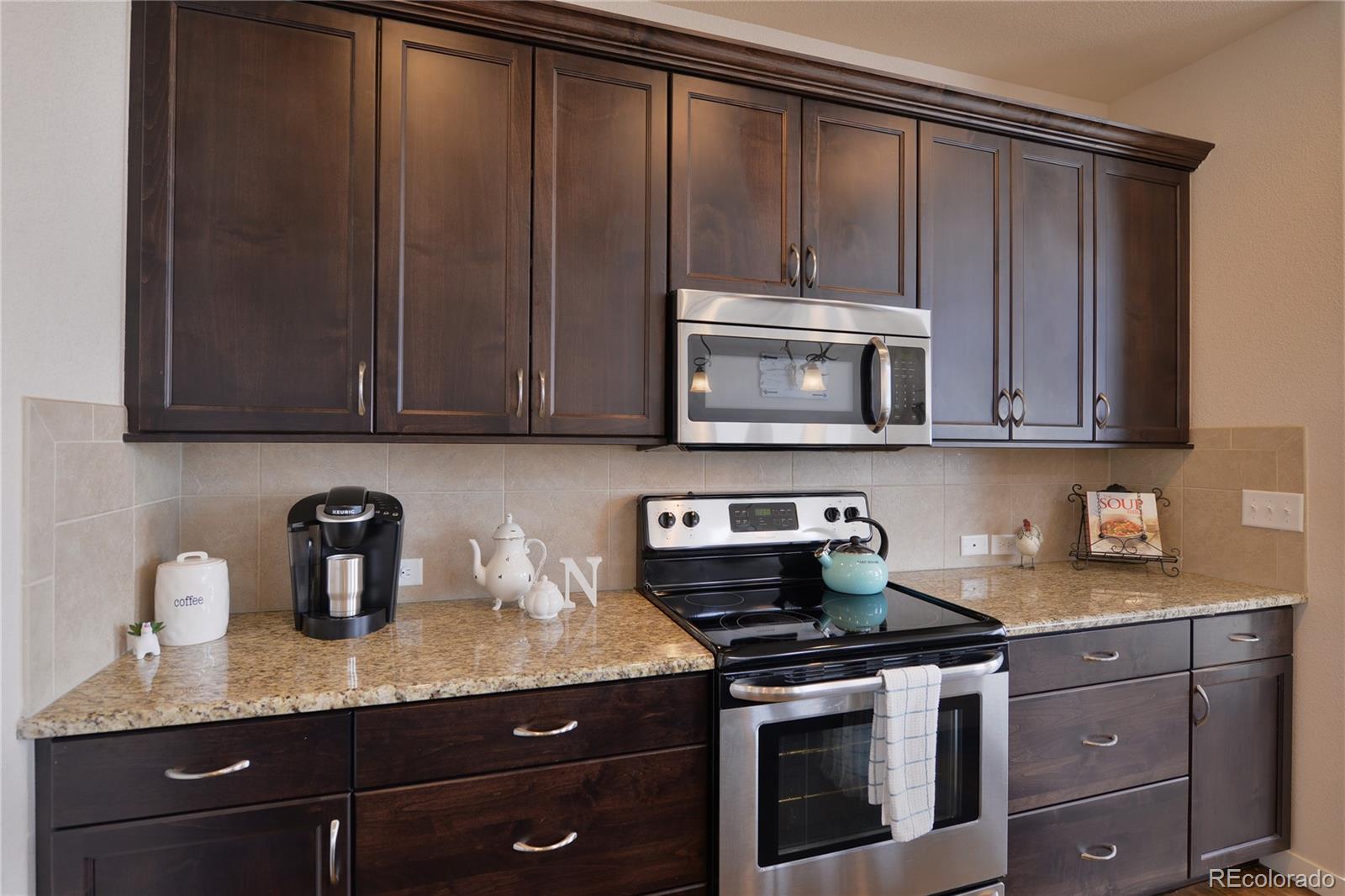 1643 Alpine Avenue Berthoud, CO 80513 - Photo 12 of 40 a kitchen with granite countertop stainless steel appliances wooden cabinets and a stove top oven