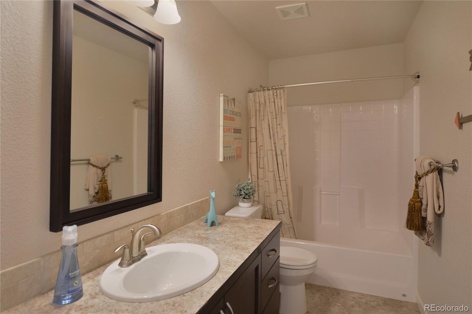 1643 Alpine Avenue Berthoud, CO 80513 - Photo 13 of 40 a bathroom with a granite countertop sink toilet a mirror and shower