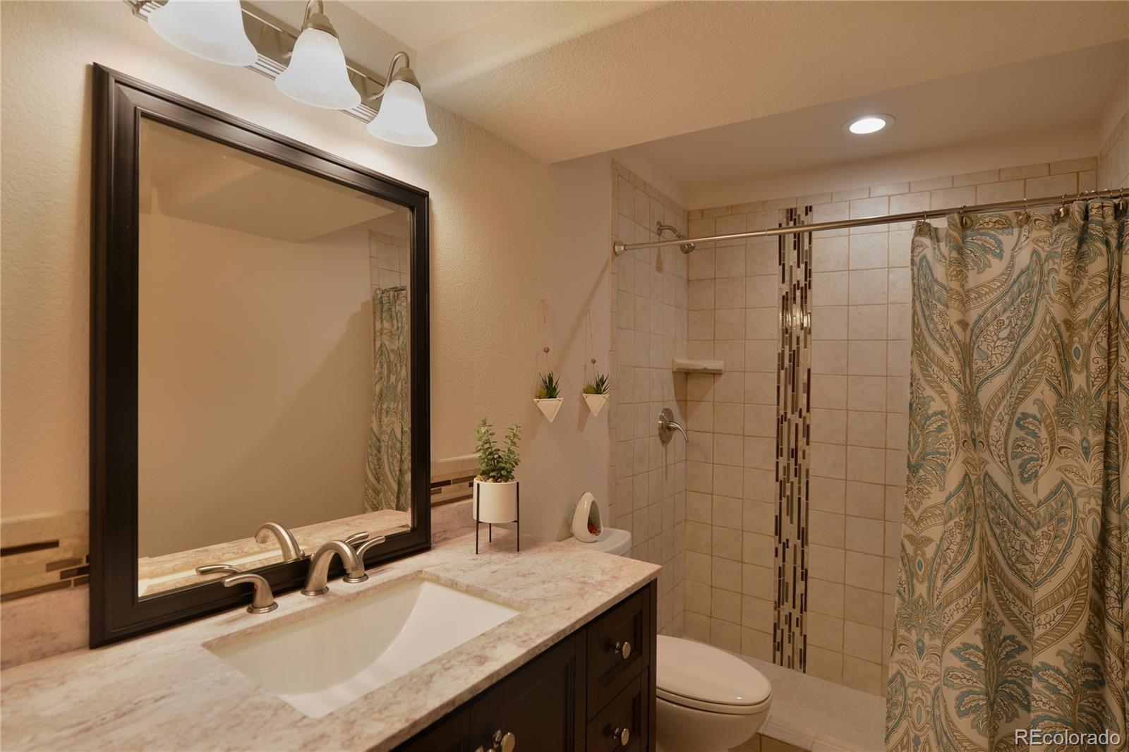 1643 Alpine Avenue Berthoud, CO 80513 - Photo 31 of 40 a bathroom with a granite countertop sink toilet and shower