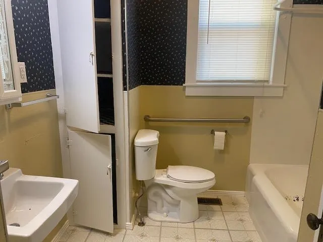 a white toilet sitting next to a bathroom sink and a tub