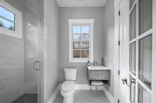 a bathroom with a granite countertop sink a toilet a mirror and shower