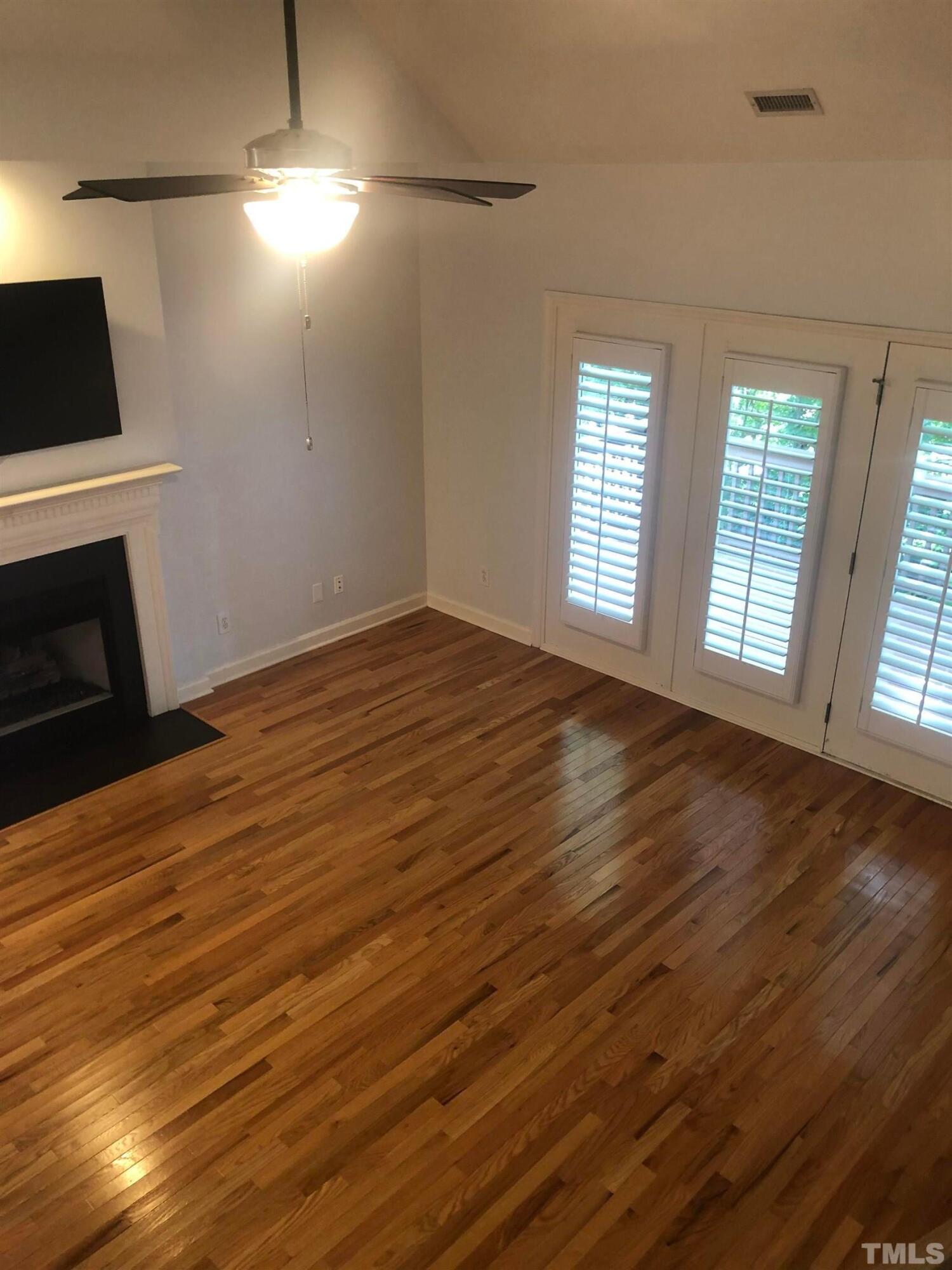 7601 Astoria Place Raleigh, NC 27612 - Photo 24 of 30 an empty room with wooden floor fireplace and windows