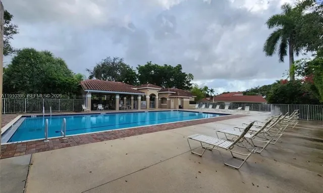 a view of swimming pool with seating area and trees in the background