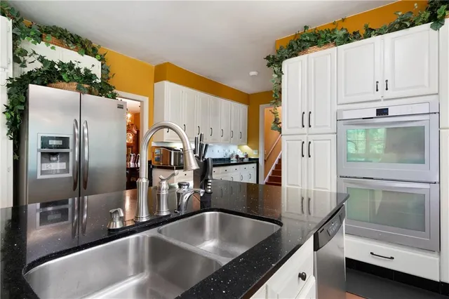 a kitchen with stainless steel appliances granite countertop a sink a stove and a refrigerator