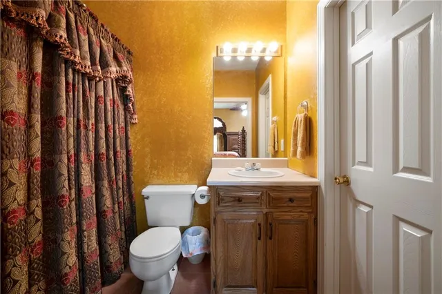 a bathroom with a granite countertop toilet sink and mirror