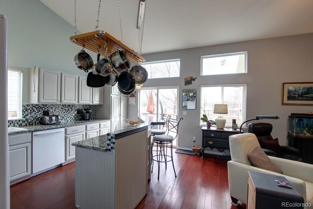 805 Nelson Park Drive Longmont, CO 80503 - Photo 8 of 33 a kitchen with stainless steel appliances granite countertop a stove top oven a dining table and chairs with wooden floor