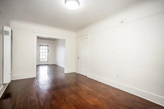 a view of an empty room with wooden floor and a window