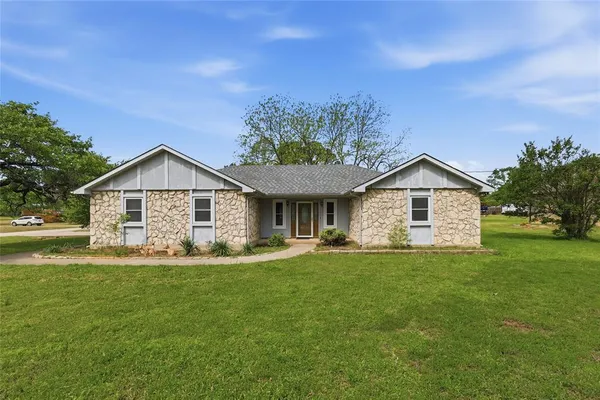 a view of a house with a yard and large trees