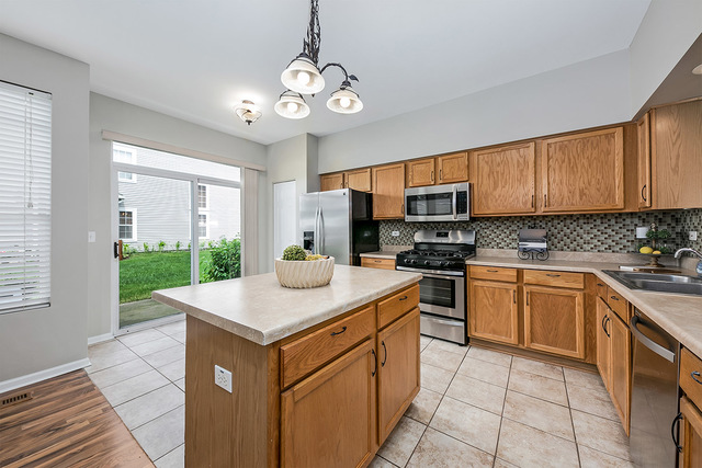 1079 Key Largo Drive Romeoville, IL 60446 - Photo 12 of 25 a kitchen with stainless steel appliances granite countertop a sink dishwasher stove top oven and cabinets
