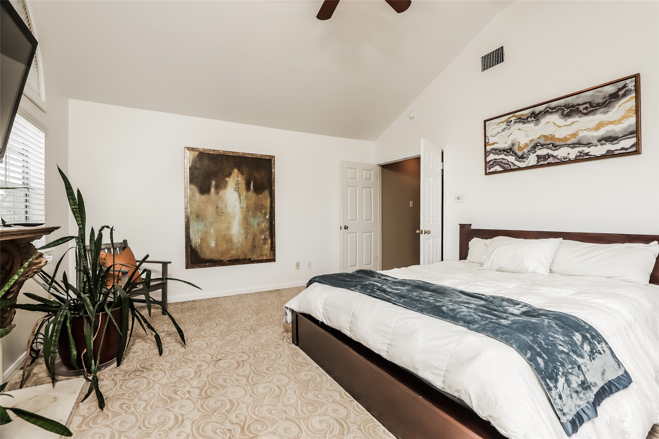 1702 Newning Avenue, Unit A Austin, TX 78704 - Photo 10 of 20 Spacious bedroom featuring vaulted ceilings, patterned carpet flooring, a ceiling fan, and a paneled door