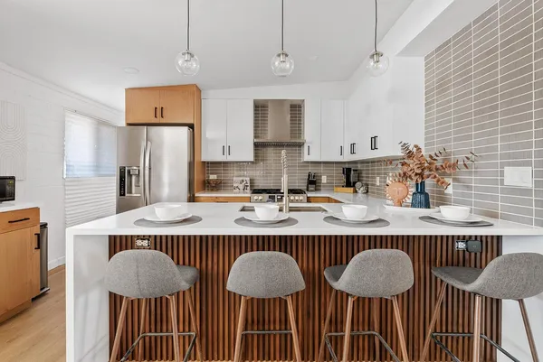 a kitchen with stainless steel appliances granite countertop a table chairs and a refrigerator