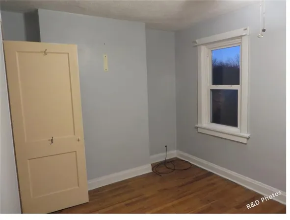 a view of an empty room with closet and mirror