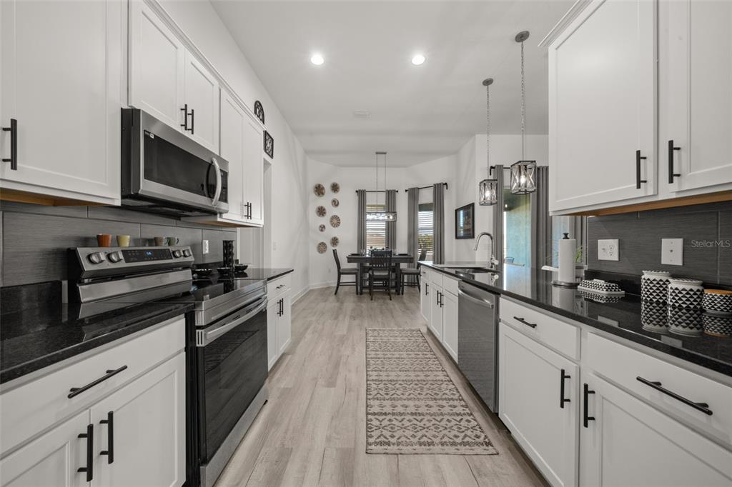 1113 Caloosa Ridge Way Babson Park, FL 33827 - Photo 40 of 77 a large kitchen with stainless steel appliances granite countertop lots of counter space a sink and dishwasher a stove top oven with wooden floor