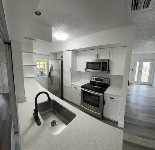 a kitchen with stainless steel appliances granite countertop a sink and a stove