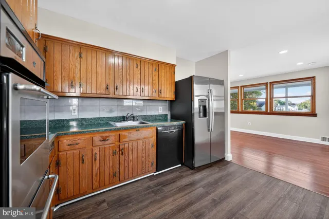 a kitchen with stainless steel appliances granite countertop a refrigerator a sink dishwasher and wooden cabinets with wooden floor