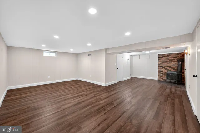 a view of an empty room with wooden floor and a fireplace