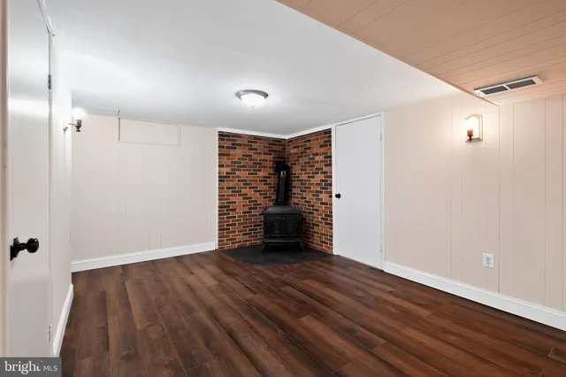 a view of an empty room with wooden floor closet and a window