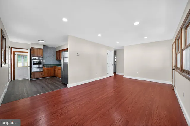 a view of a big room with wooden floor and a kitchen