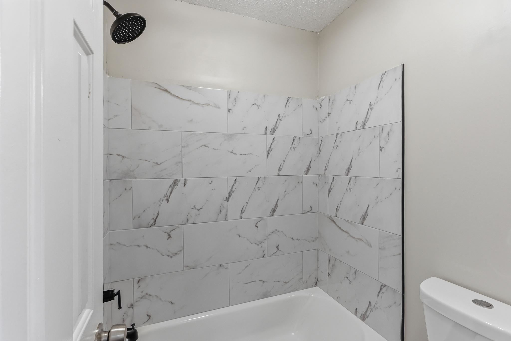 4101 Long Creek Road Memphis, TN 38125 - Photo 16 of 36 Bathtub with subway-style white tile surround featuring grey veining
