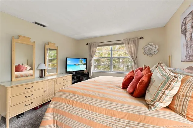 a bedroom with a bed a mirror on dresser and a window