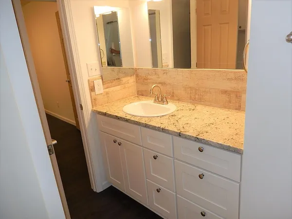 a bathroom with a granite countertop sink and a mirror