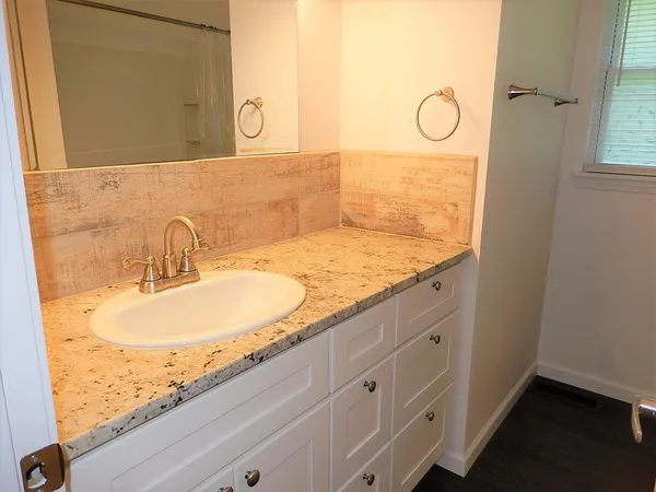 a bathroom with a granite countertop sink and a mirror